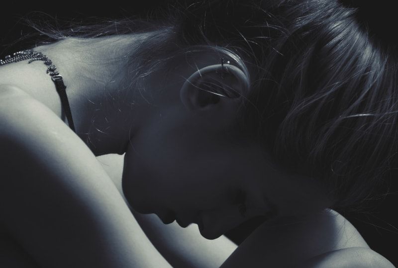 das Mädchen, das ihren Kopf auf ihr Knie lehnte