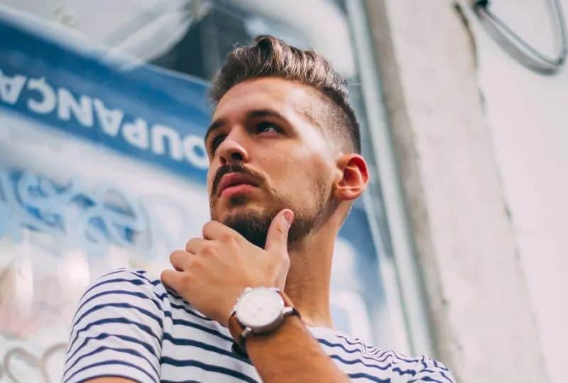 Ein Mann mit Bart und moderner Frisur posiert