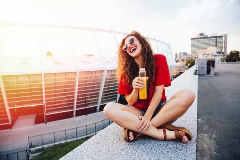 Das Mädchen sitzt an der Wand und trinkt Saft