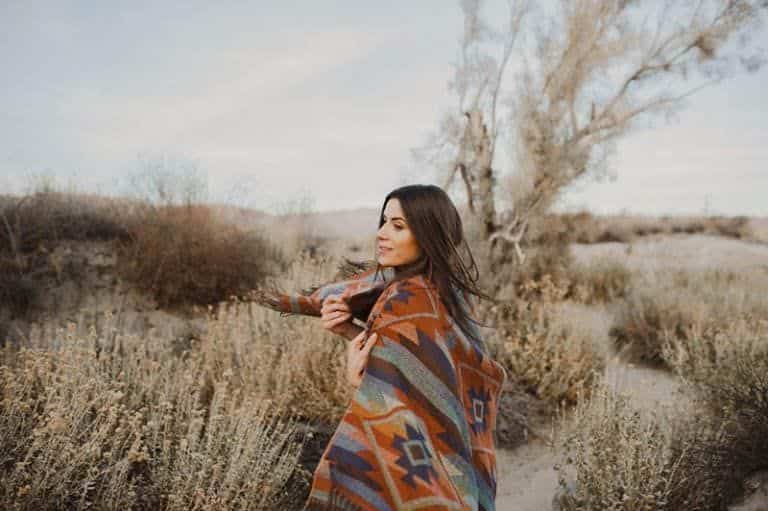 Ein Mädchen, das mit einer Decke bedeckt ist, geht durch ein Feld