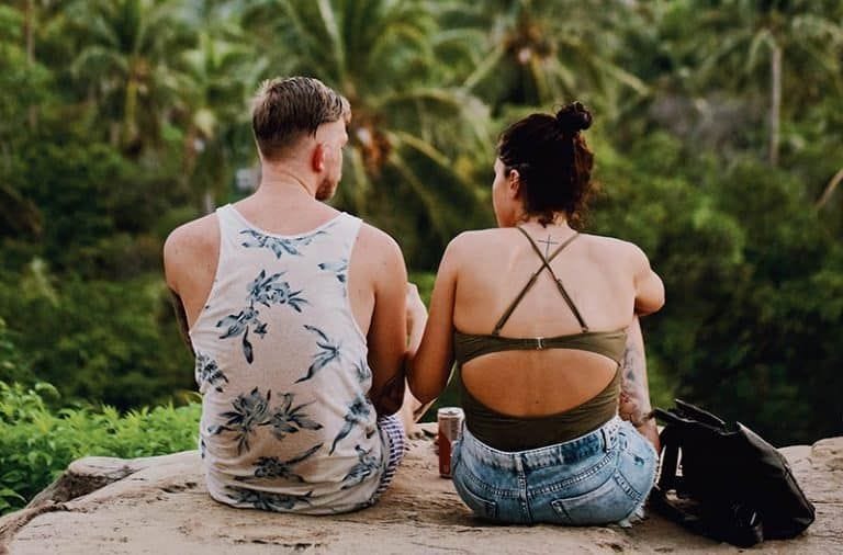 zwei junge Männer sitzen auf einem Felsen im Regenwald