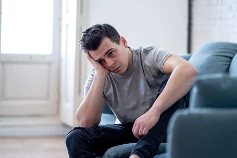 depressiver Mann sitzt im Wohnzimmer