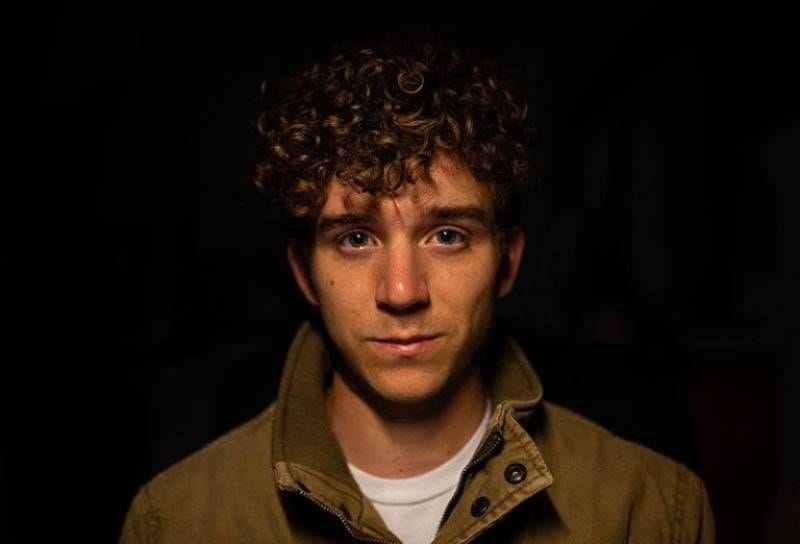 süßer trauriger junger Mann im Dunkeln