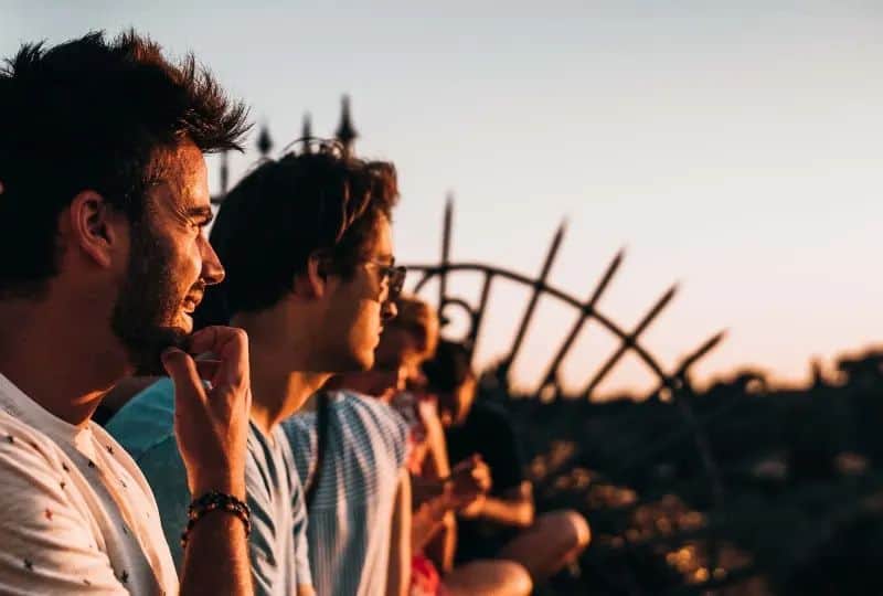 Mann sitzt auf Zaun nach rechts unter goldener Stunde