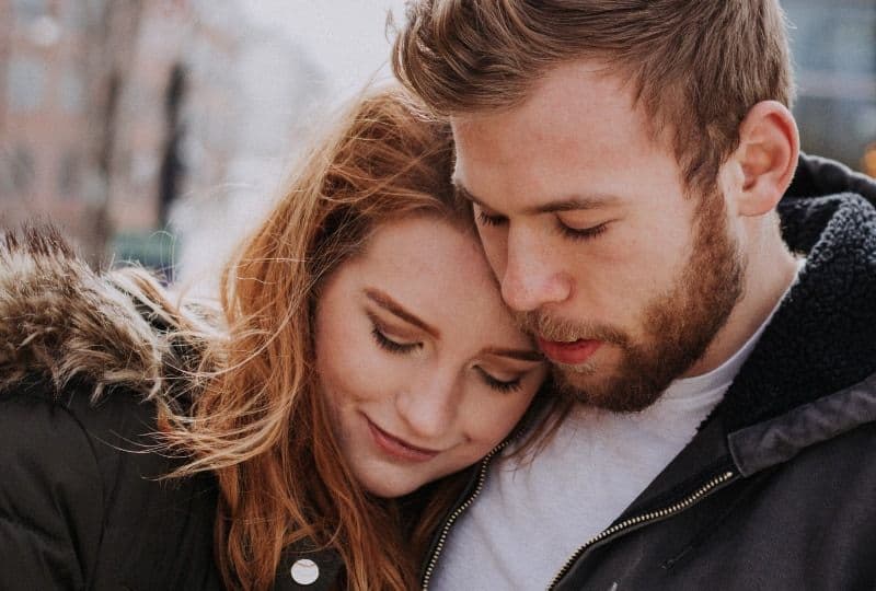 Mann umarmt Frau, die auf Straße steht