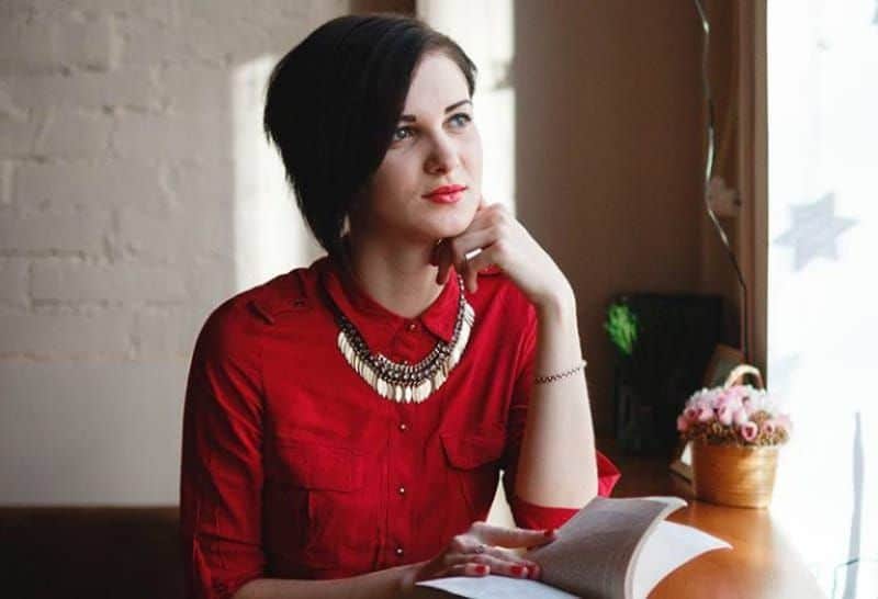 Eine Frau in einem roten Hemd schaut aus dem Fenster