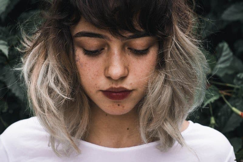 Eine unglückliche Frau mit Locken steht mit gesenktem Kopf da