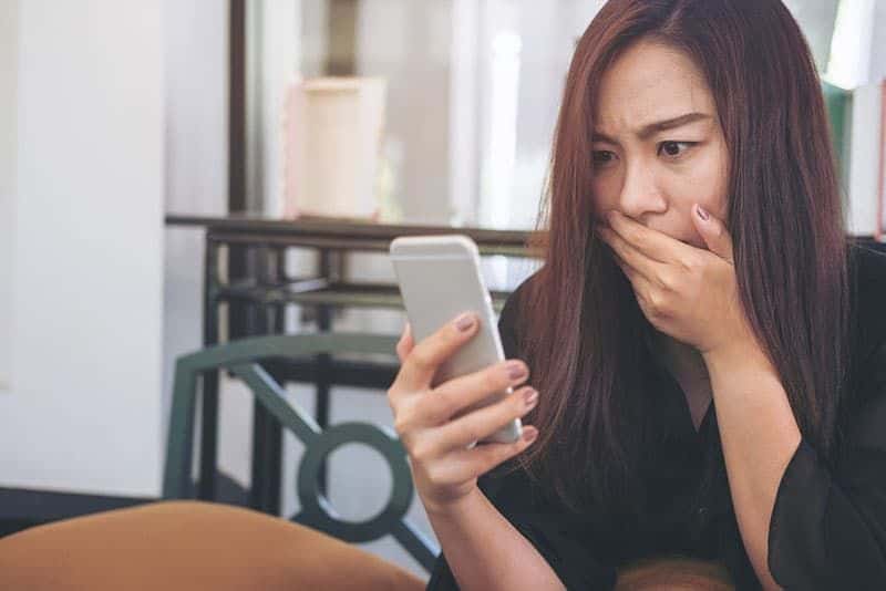 überraschte Frau schaut auf Telefon