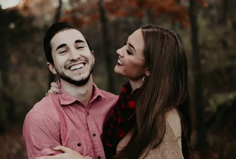 Ein Paar lacht und geht im Wald spazieren