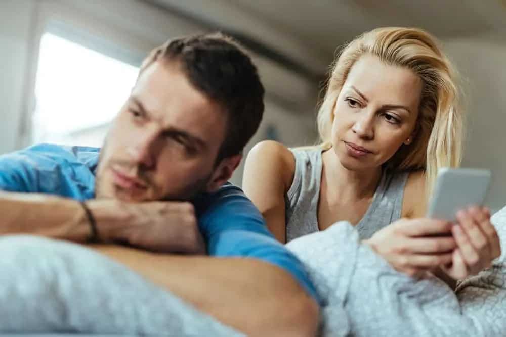 Eine Frau mit einem Telefon sieht ihren Mann an, der sie ignoriert