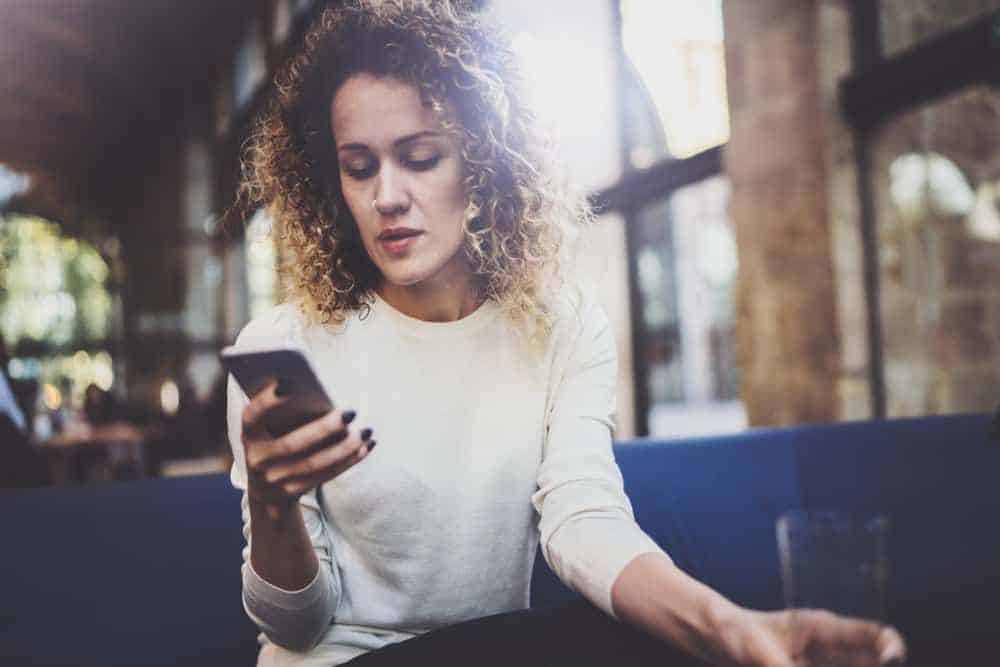 Ein hübsches Mädchen schaut traurig auf ihr Handy