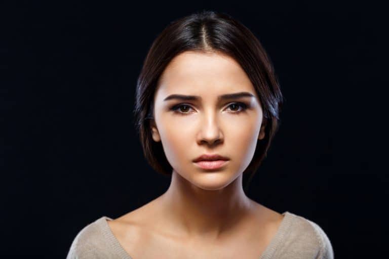 ein trauriges Mädchen, das vor einem schwarzen Hintergrund aufwirft