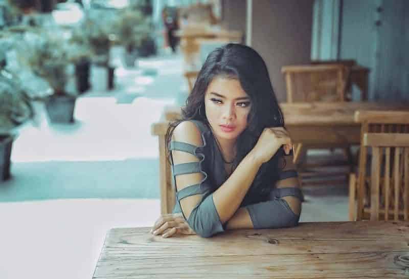 Frau im grauen langärmeligen Oberteil sitzt auf Stuhl