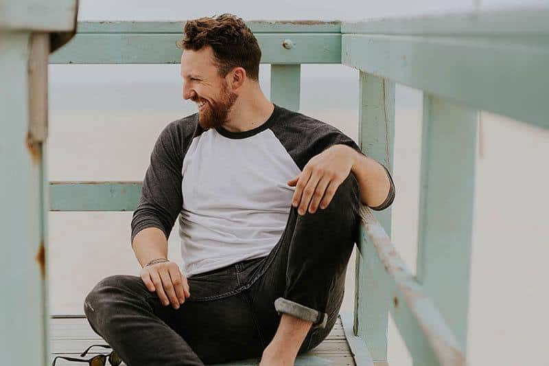 Ein lächelnder Mann mit Bart sitzt