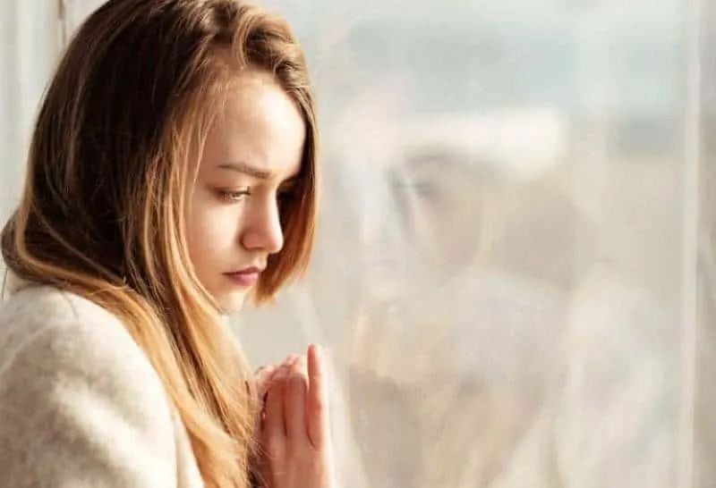 Ein trauriges Mädchen schaut aus dem Fenster