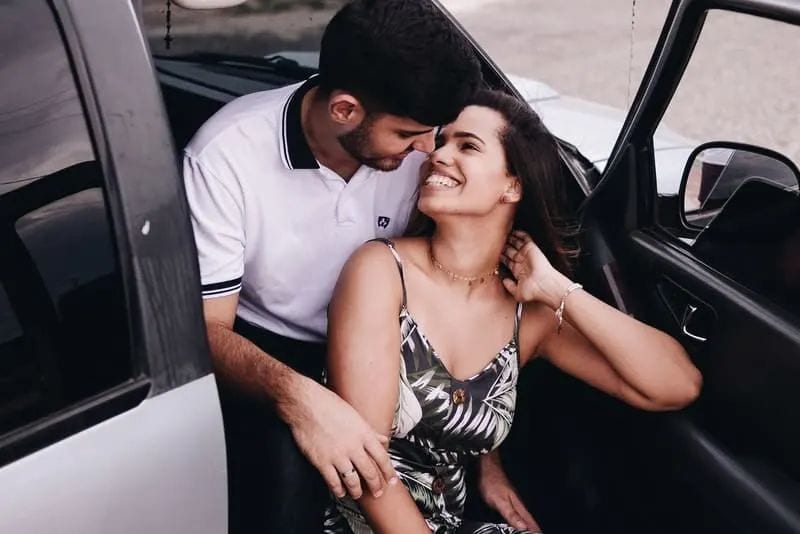 Im Auto sitzt in einer Umarmung ein lächelndes Liebespaar