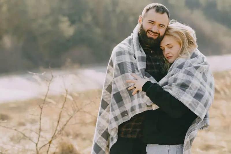 ein romantisches Paar unter einer Decke, die in einem Weizenfeld steht