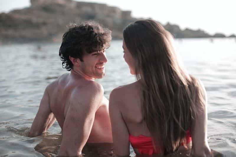 lächelndes Liebespaar, das im Flachwasser des Meeres liegt