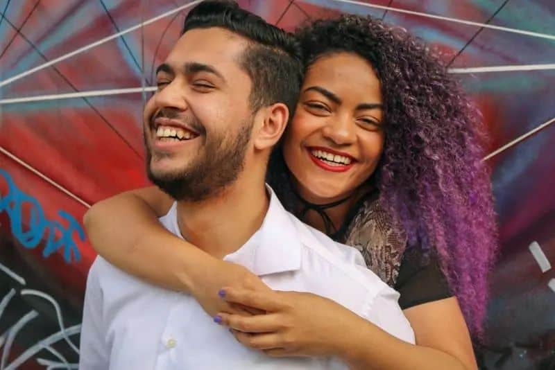 Die Frau hinter ihren Armen umarmt ihren Mann