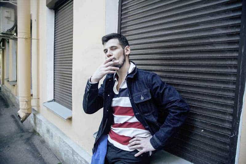 Mann raucht draußen Zigarette