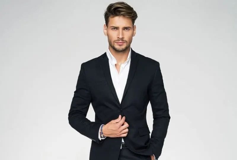 ein ernster Mann in einem Anzug, der vor einem grauen Hintergrund aufwirft(1)