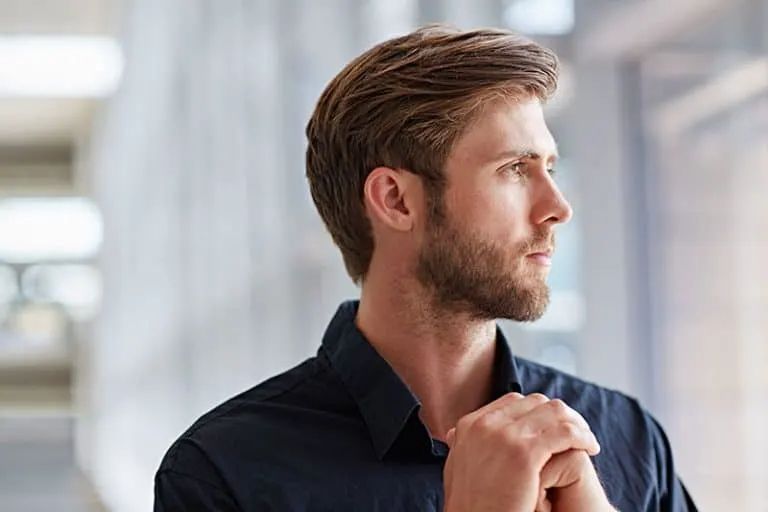 Ein braunhaariger Mann mit Bart schaut aus dem Fenster