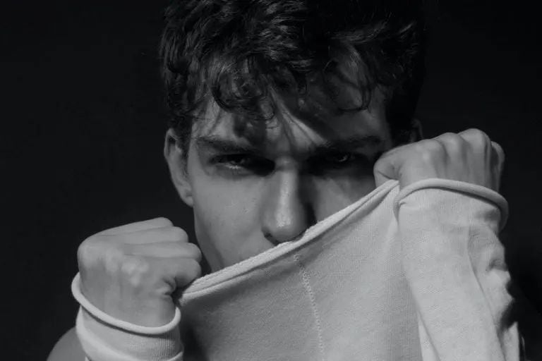 Ein attraktiver junger Mann posiert in einem Sweatshirt