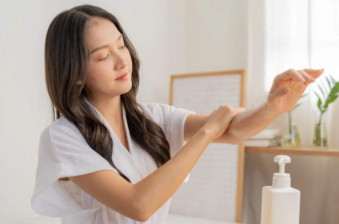Frau trägt Feuchtigkeitscreme auf ihren Arm auf