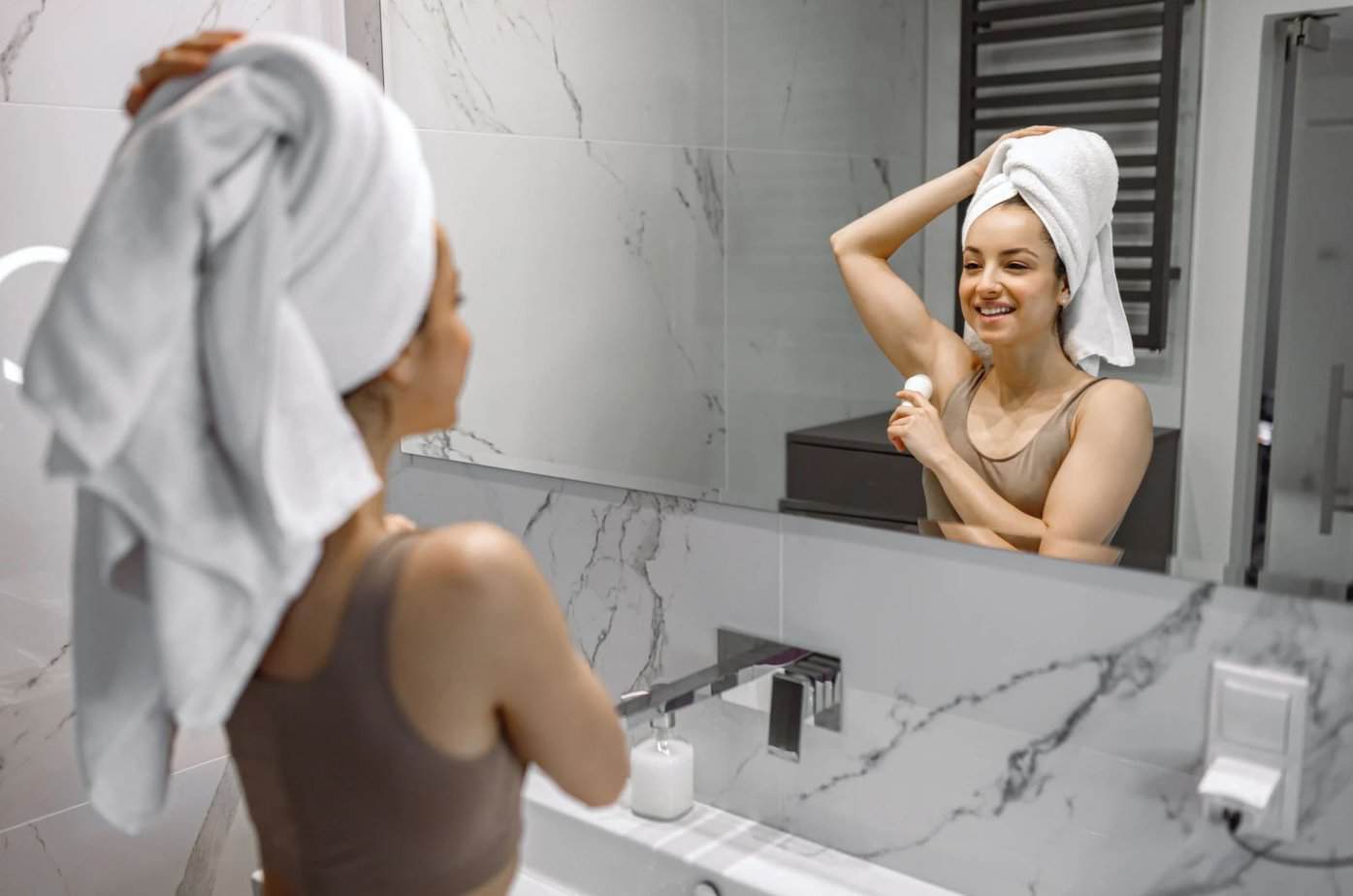 Frau in weißem Handtuch, die festes Deodorant aufträgt