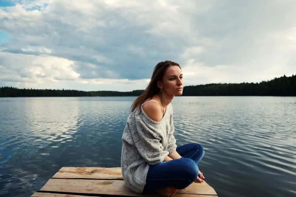 Jeg håper det vil hjemsøke deg for alltid at du såret meg Auf dem Pier des Sees sitzt eine traurige nachdenkliche Frau