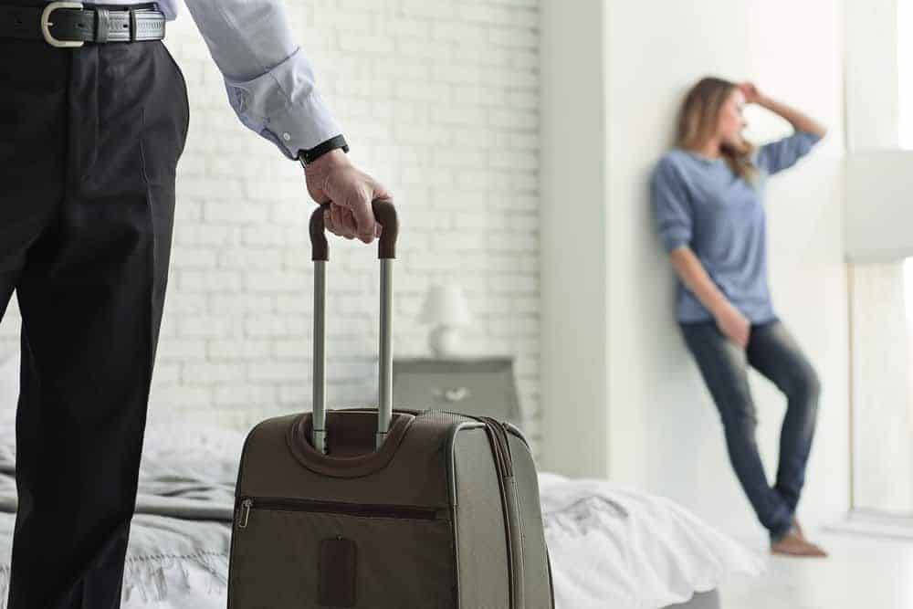 Ein Mann mit einem Koffer hinterlässt eine traurige Frau