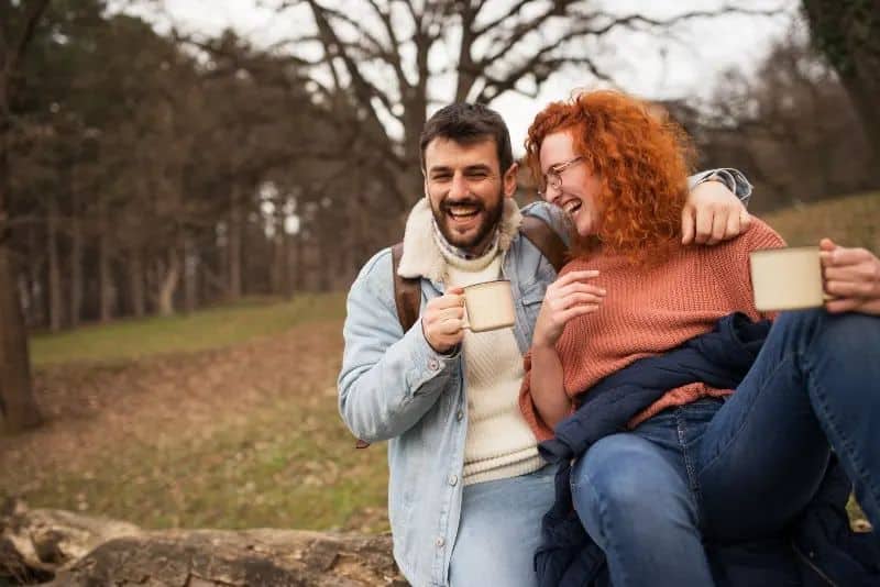 ein paar trinken kaffee in der natur und lachen