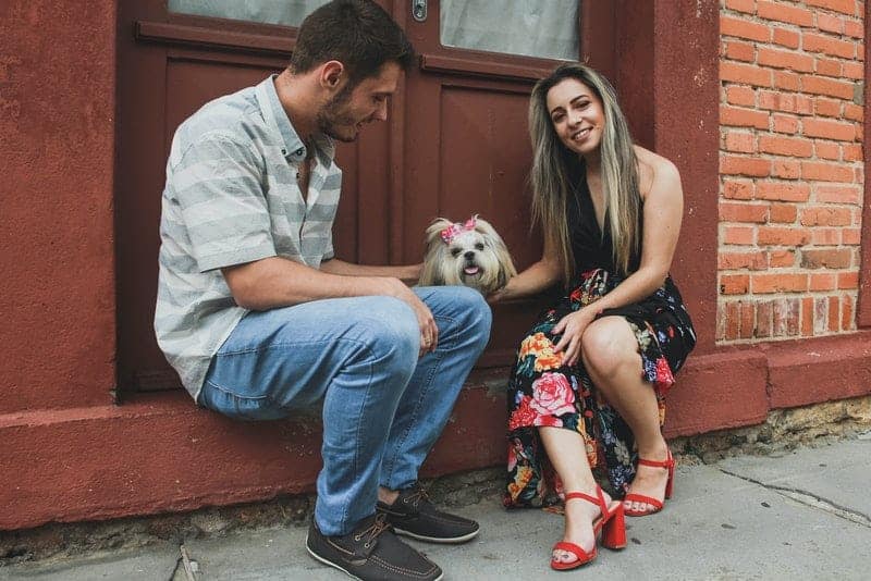 ein glückliches Liebespaar mit ihrem Haustier, das vor der Tür sitzt