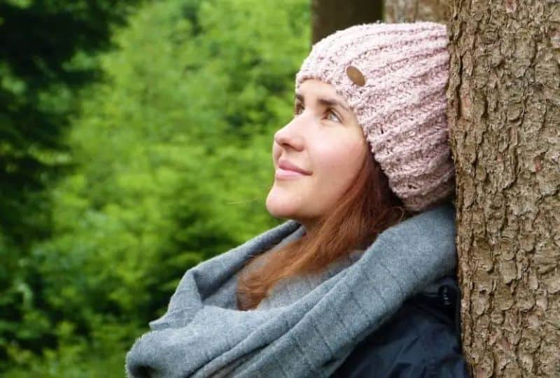 eine-lächelnde-Frau-im-Wald-die-zum-Himmel-aufblickt