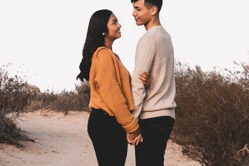 ein liebendes Paar, das Hände hält und auf einem sandigen Weg steht