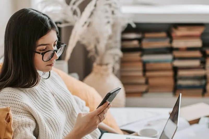 eine Frau sitzt und schaut auf ein Smartphone