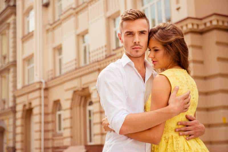 Mann beschützt seine Freundin und umarmt