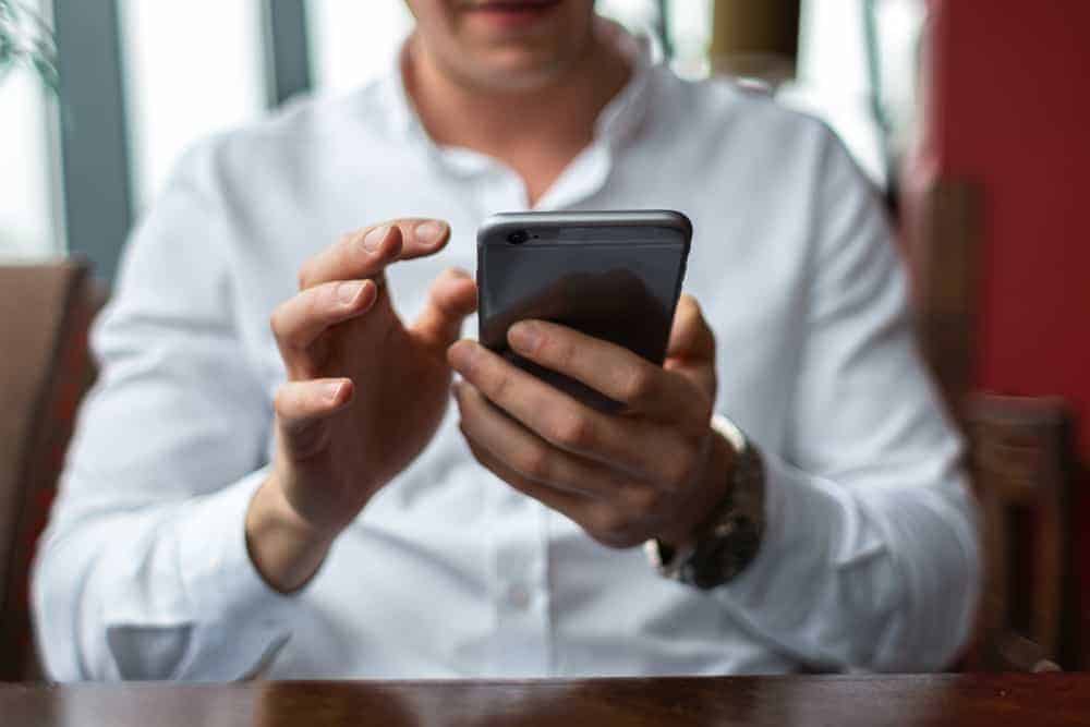 Ein Mann in einem weißen Hemd benutzt ein Smartphone