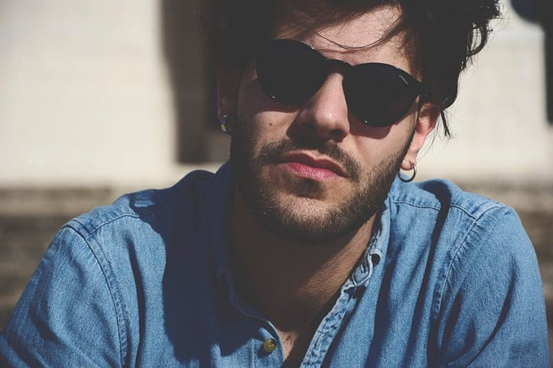 Ein selbstbewusster Mann mit Sonnenbrille und blauem Jeanshemd