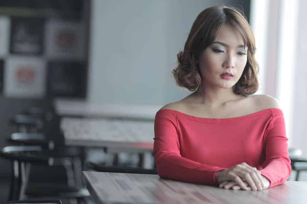 Eine traurige Frau in einem rosa T-Shirt sitzt in einem Café