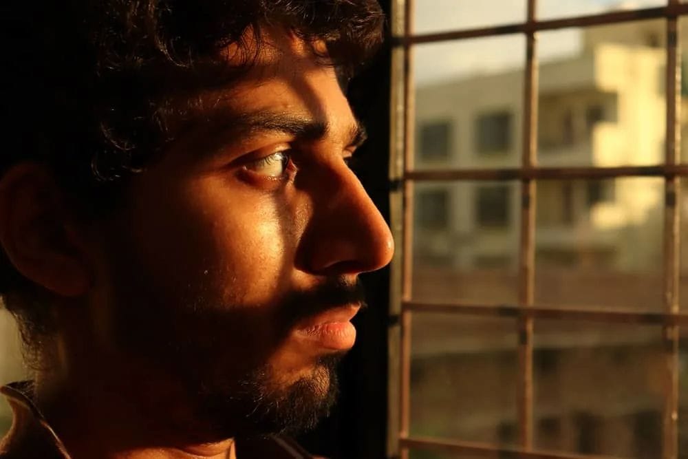 ein Porträt eines traurigen Mannes, der aus dem Fenster schaut