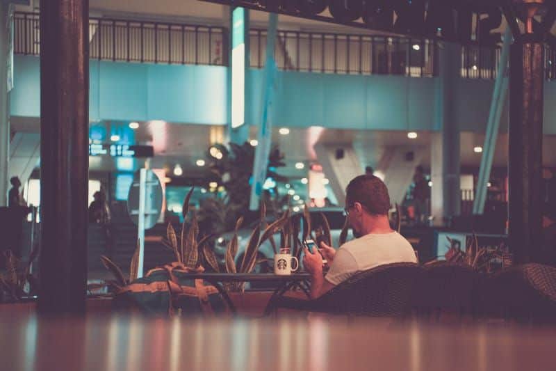 Hvis han skriver disse 10 meldingene til deg, er han en jackpot-kjæreste Mann, der Telefon benutzt, das auf Stuhl vor weißem Becher sitzt