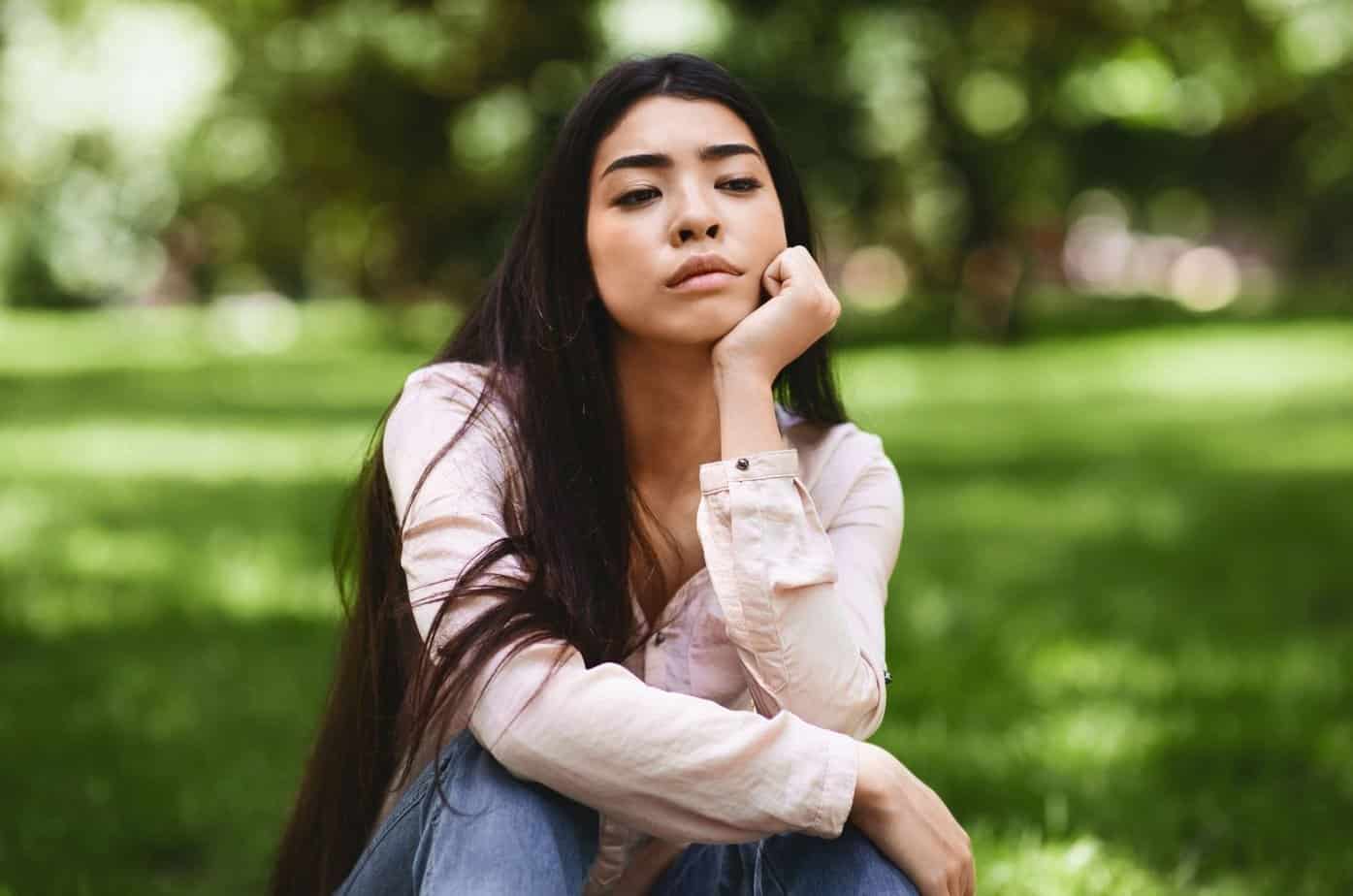 Hvorfor det er så smertefullt å bryte med en narsissist, og hvordan du kan komme deg gjennom det junge frau sitzt auf gras