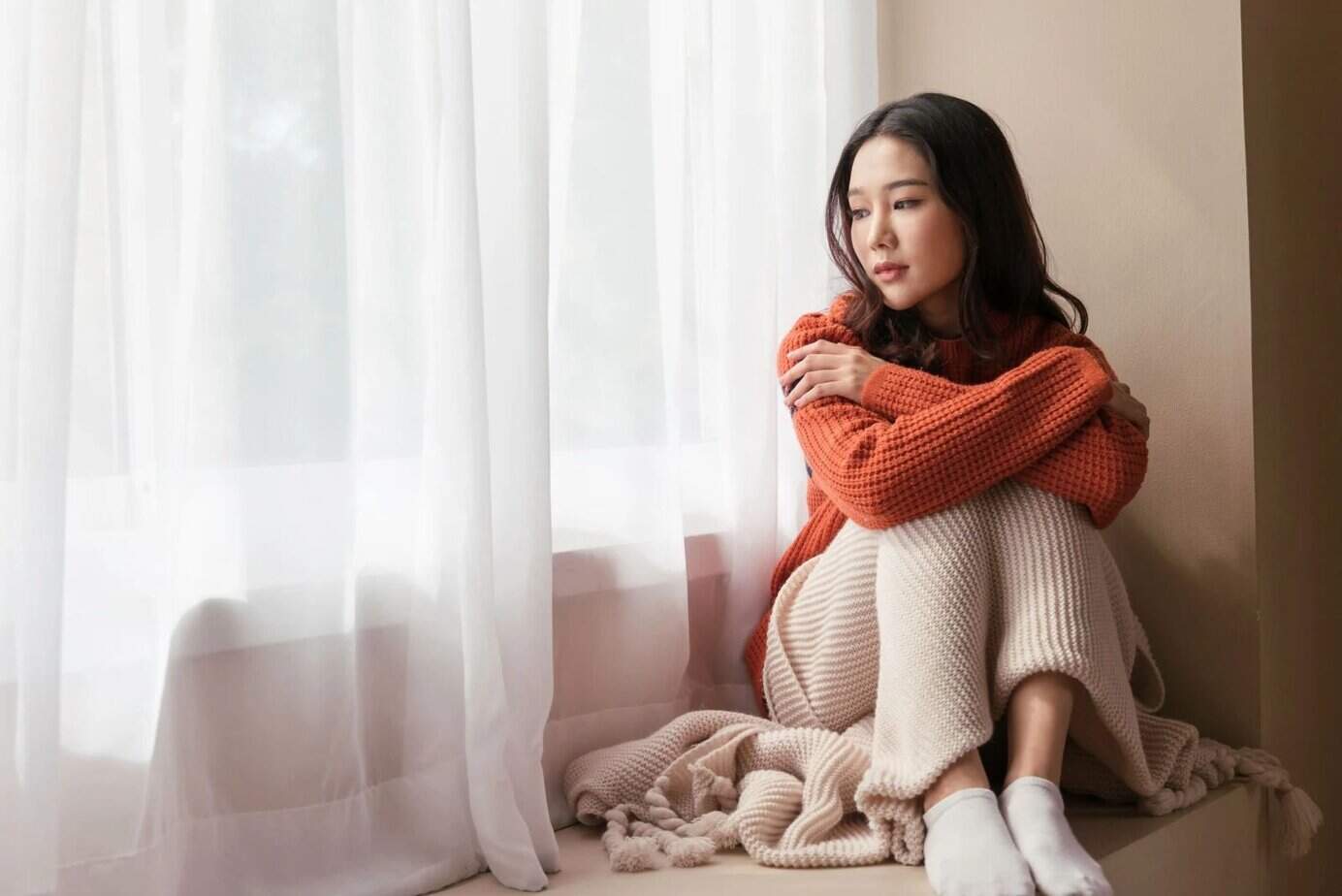 traurige Frau sitzt auf der Fensterbank