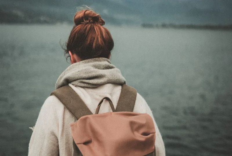 Frau steht in der Nähe ruhiges Gewässer]