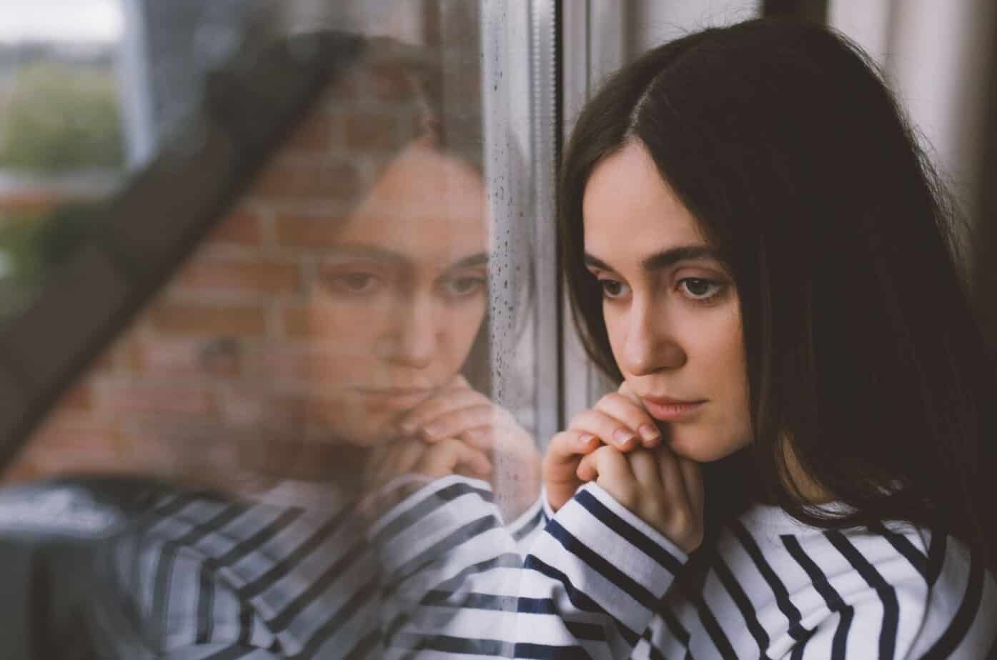 Frau am Fenster denkt nach