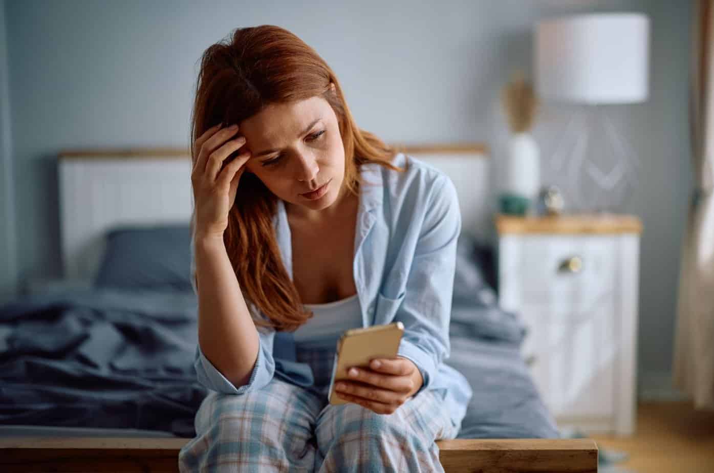 frau liest nachricht am bett