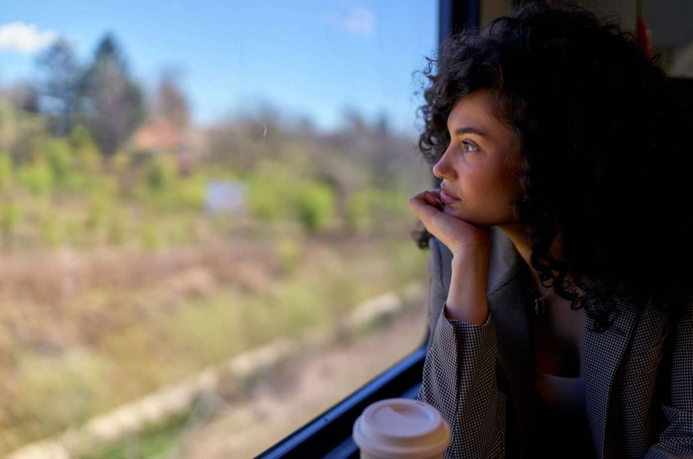 frau schaut aus zugfenster