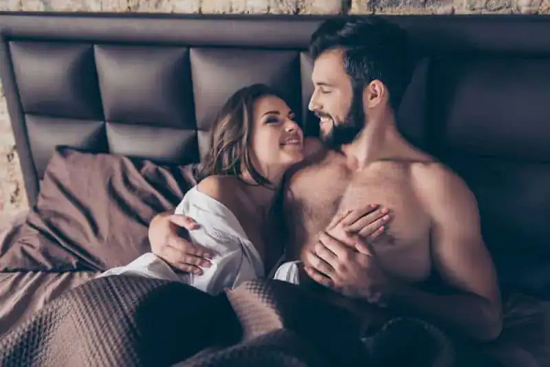 atemberaubende Frau, die ihren Mann im Bett umarmt