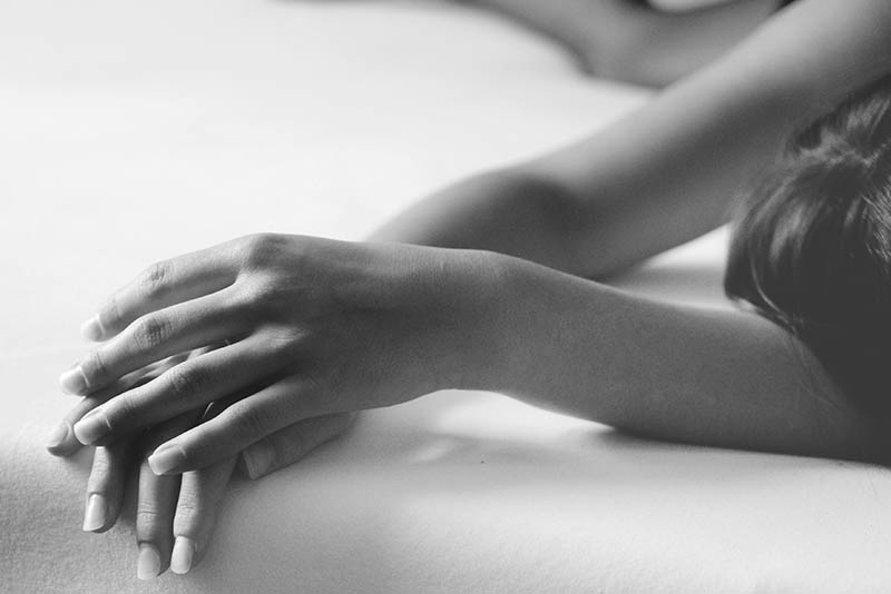 die Hände einer jungen Frau, die auf einem Bett liegt